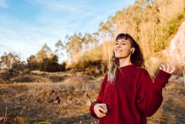 Junge lächelnde Hipsterfrau, die in der Natur mit dem Handy Musik hört — Stockfoto