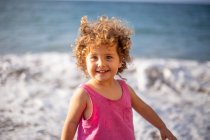 Lustiges Mädchen am Sandstrand in Wassernähe mit Schaum und Spritzern im Sommer — Stockfoto