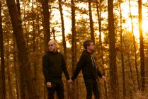 Homosexual couple holding hands and walking on way in forest — Stock Photo
