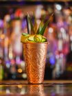 Tazza di metallo con cocktail di frutta su sfondo sfocato brillante — Foto stock