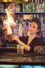 Schöne Barfrau spritzt Flüssigkeit in Becher, während sie Cocktails in einer modernen Bar zubereitet — Stockfoto