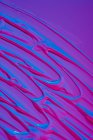 Poça de tinta acrílica néon brilhante espalhar sobre fundo roxo vívido — Fotografia de Stock