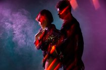Vue latérale de l'homme et de la femme attrayants dansant danse sensuelle près de fumée sous un éclairage lumineux — Photo de stock