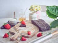 Café da manhã com panquecas e morangos na mesa da cozinha com flores — Fotografia de Stock
