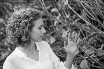 Jovem mulher sonhadora tocando ramos secos de arbusto no fundo borrado — Fotografia de Stock