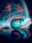 Кришталева куля на поверхні з відображенням біля абстрактних сяйв — стокове фото