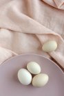 White eggs served on plate on pink fabric — Stock Photo