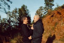 Feliz pareja homosexual abrazándose en el camino en el bosque en el día soleado - foto de stock