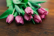 Bouquet of fresh pink tulips on wooden surface — Stock Photo