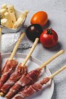 Gressinis with spanish typical serrano ham on white plate with fresh tomatoes and cheese — Stock Photo