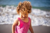 Смешная девушка на песчаном берегу у воды с пеной и брызгами летом — стоковое фото