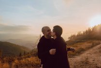 Romantica coppia omosessuale che si abbraccia sul sentiero in montagna nella giornata di sole — Foto stock