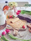 Frühstück mit Pfannkuchen und Erdbeeren auf Küchentisch mit Blumen — Stockfoto
