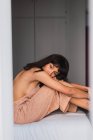 Jovem mulher nua vestido sentado na cama no quarto — Fotografia de Stock