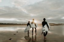 Personnes avec planche de surf marchant près de la mer — Photo de stock