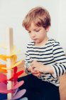 Loira bonito menino jogando com waldorf soando torre com mármores — Fotografia de Stock