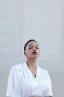 Мода короткие волосы этническая женщина модель в белой рубашке позирует против серой стены — стоковое фото