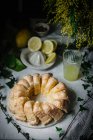 From above cut Bundt cake and glass of lemon juice on rustic table — Stock Photo