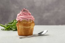 Köstliche hausgemachte Cupcake auf verschwommenem Hintergrund mit Teelöffel — Stockfoto
