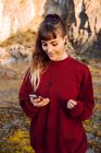 Junge Hipster-Frau mit Piercing und Kopfhörer hört Musik mit Handy und geht auf Landstraße — Stockfoto