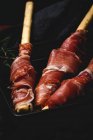 Gressinis con jamón serrano típico español en bandeja sobre tela negra - foto de stock