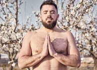 Hombre sin camisa meditando en el jardín de primavera - foto de stock
