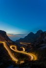 Larga exposición de luces de sendero en la noche entre montañas - foto de stock
