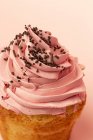 Primer plano de delicioso cupcake casero sobre fondo rosa - foto de stock