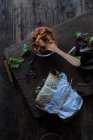 Sandwich de paté de tomates secos, ensalada fresca y col en bandeja cerca de cuchillo sobre tabla de madera sobre fondo negro - foto de stock