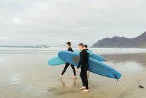 Personnes avec planche de surf marchant près de la mer — Photo de stock