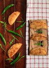 Rissóis cozidos em casa e pimentas verdes frescas com folhas de arugula na mesa de madeira — Fotografia de Stock