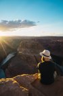 Вид сзади на бородатого парня, смотрящего на красивый каньон и спокойную реку в солнечный день на западном побережье США — стоковое фото