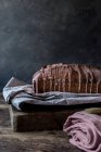 Gâteau orange frais savoureux aux graines de pavot et garniture sur papier artisanal sur fond noir — Photo de stock