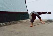 Chico realizando handstand mientras bailando cerca de pared de moderno edificio - foto de stock
