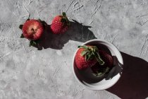 Frische Erdbeeren in Schale und auf grauer Oberfläche — Stockfoto