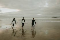 Menschen mit Surfbrett zu Fuß in der Nähe des Meeres — Stockfoto