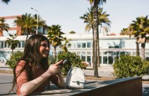 Teenie-Mädchen schaut an einem sonnigen Tag auf der Straße auf ihr Smartphone — Stockfoto