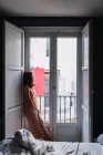 Giovane donna magra in piedi vicino a una grande finestra in camera da letto — Foto stock