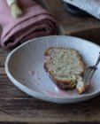 Dall'alto fetta di torta arancione saporita fresca con semi di papavero e condimento su piatto vicino a forchetta su sfondo di legno — Foto stock