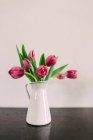 Bouquet of fresh pink tulips in vase on grey table — Stock Photo