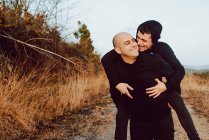 Glückliches homosexuelles Paar hat Spaß auf dem Weg zwischen Pflanzen in den Bergen — Stockfoto