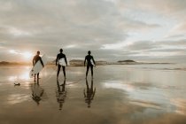 Люди с доской для серфинга, гуляющие у моря — стоковое фото
