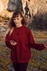 Giovane donna hipster riflessivo ascoltare musica con il telefono cellulare e camminare nella natura — Foto stock