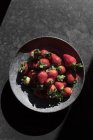 Fresh red strawberries in bowl on dark background — Stock Photo