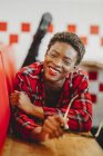 Усміхнений афроамериканець жінка лежала на місцях в кафе і дивиться на камеру — стокове фото