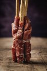 Gressini con prosciutto tipico spagnolo serrano su tavola rustica in legno — Foto stock