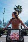 Junge hübsche Frau fährt bei sonnigem Wetter auf Roller auf Parkplatz zurück — Stockfoto