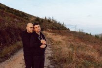 Casal homossexual sonhador abraçando na rota na natureza — Fotografia de Stock
