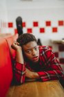 Confiante mulher afro-americana deitada em assentos no café e olhando para a câmera — Fotografia de Stock