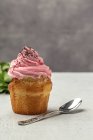 Köstliche hausgemachte Cupcake auf verschwommenem Hintergrund mit Teelöffel — Stockfoto